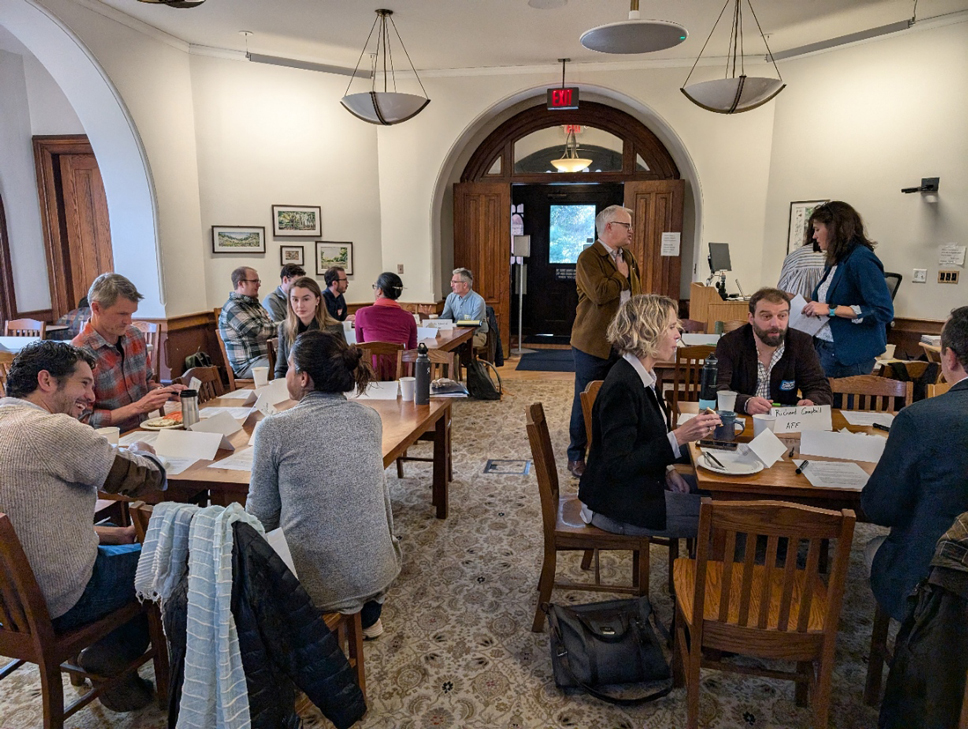 Participants of SHIFTCM sitting in small groups at tables discussing